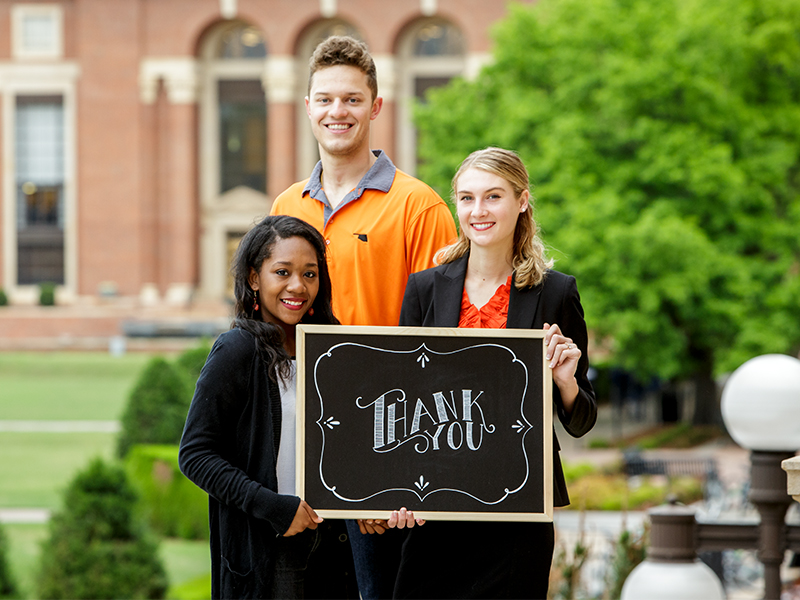 Students saying thank you with a chalk sign