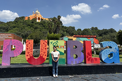 Mili Jha in Puebla in front of a large colorful sign