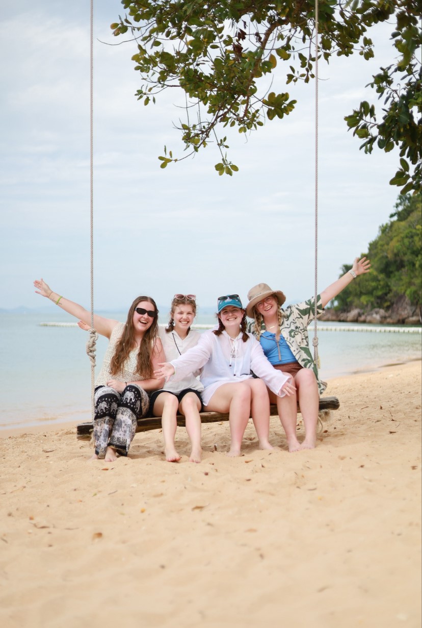 Students on a ropeswing on the beach in Thailand